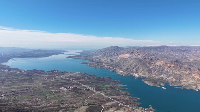 4K aerial drone shot moving forward toward a scenic lake with a gentle left pan over a majestic mountain landscape. Natural lighting, flat color profile, grading friendly.