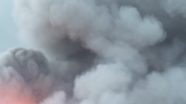 Thick volcanic ash clouds and smoke billowing with fiery orange glow