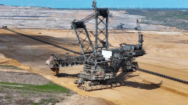 bucket wheel excavator dwarfs the landscape at hambach lignite mine dense row of wind turbines spans horizon second excavator works distant terrace conveyor belt stretches toward camera kerpen germany