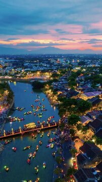 4k,Time lapse Vertical video of Hoi An Ancient Town at dusk, Vietnam, featuring colorful lantern boats, crowded riverside promenade, and vibrant tourism atmosphere along the Thu Bon River.