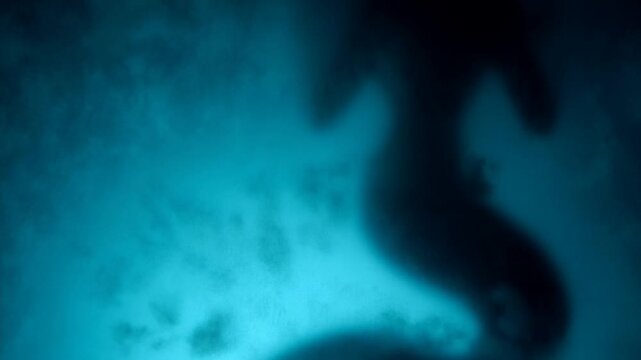 Abstract blue smoky background with soft dark blurred shapes and glowing texture