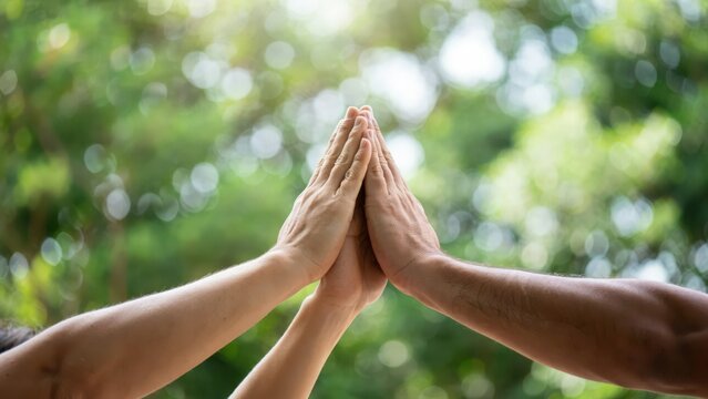 Diverse hands coming together in a pyramid shape symbolizing unity teamwork friendship and strength outdoors