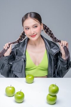 Trendy stylish woman balancing green apple on head, showcasing playful attitude, fashion beauty, quirky balance, youthful confidence, creative diet concept, modern wellness, and edgy cool lifestyle.