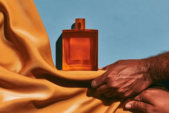 Gold silk fabric draped beside a clear perfume bottle with amber liquid, featuring a blank label mockup for luxury retail and duty-free layouts