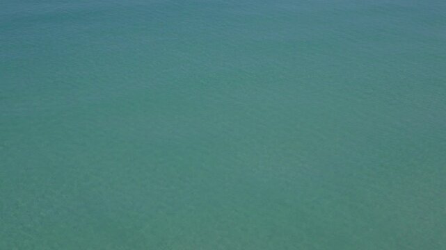Views down from cliffs of clear blue calm sea at Newquay, Cornwall, England on a hot sunny June day.