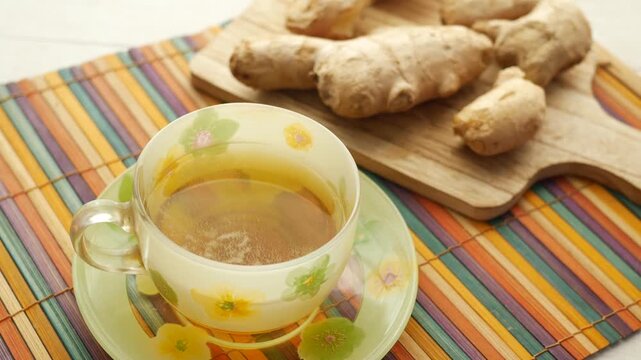 Fresh ginger tea in cup on wooden board with raw ginger root roots for healthy lifestyle and wellness