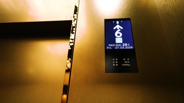 Digital elevator display panel showing floor numbers rising in modern skyscraper with reflection on metallic surface.