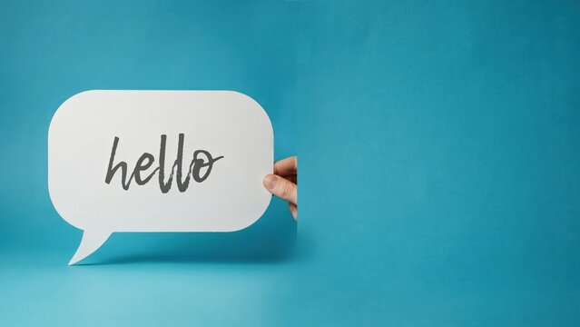 Minimalist hello speech bubble on blue background, white paper chat icon with greeting text, hand holding message bubble for communication