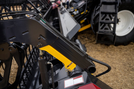 Close-up of yellow safety lock bracket and hydraulic cylinder mounted on black metal implement frame.