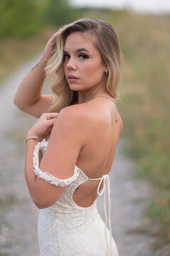 Young blonde woman posing in elegant lace dress outdoor