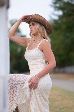 Blonde woman wearing western lace dress and cowboy hat