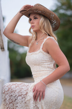 Woman wearing cowboy hat and lace dress outdoors
