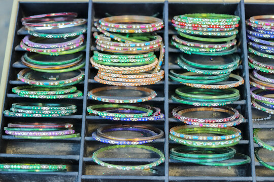 Close up of colorful vintage bangles and bracelets sorted in a dusty black display tray. Authentic secondhand costume jewelry merchandising concept for flea market retail.