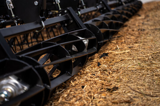 Close-up view of black metal roller compactor section on agricultural disc harrow frame standing outdoors.
