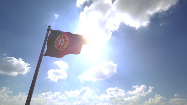 Portugal Flag waving on a Flagpole from a Moving Angle in front of a blue sky with clouds	