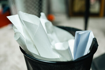 Paper wastebasket filled with crumpled white paper and empty disposable cup, highlighting office...