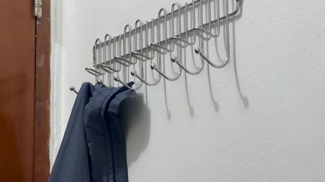 Close up of a person hanging a jacket and pants on a modern minimalist wall hook