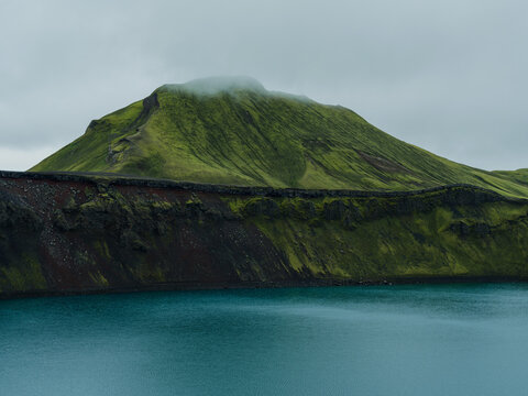 Bright green moss-covered volcanic and turquoise lake in Iceland