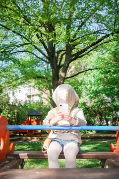 Hooded anonymous child play in playground