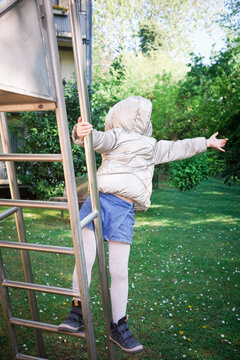 Child climbing playground ladder in garden