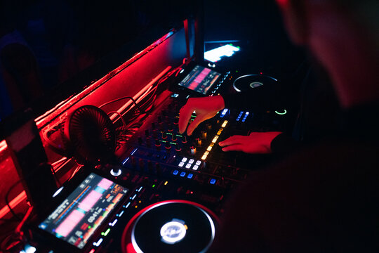 DJ Performs Set at Nightclub With Colorful Lights and Sound Equipment
