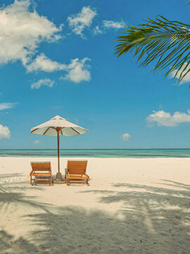 Peaceful beach umbrella sunbeds palm shade sandy beach calm ocean blue sky sunny summer tropical paradise. Perfect summer vacation travel scene. Relaxing romance love couple idyllic holiday background