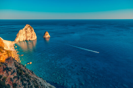 Stunning aerial Greek calm sea rocks deep blue bay boat summer paradise sunset light horizon view. Peaceful summer travel scene nature. Scenic sky Mediterranean aerial coastal vacation background