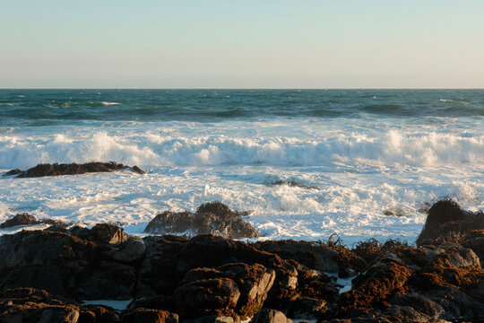 Sea foam crashing on rocky shore