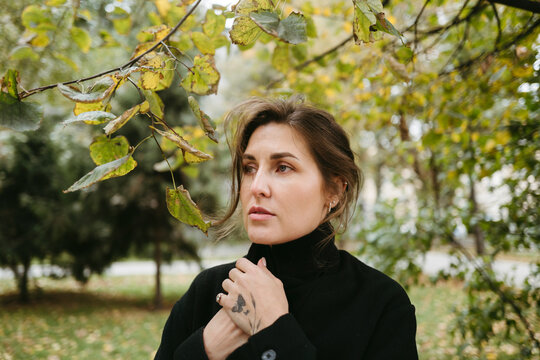 Woman in a Black Coat Enjoys Autumn in a Serene Park