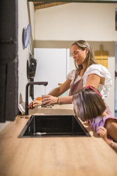 Pregnant mother with her daughter in a rustic kitchen.