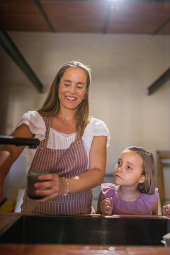 Pregnant mother with her daughter in a rustic kitchen.