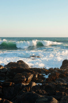 Ocean waves breaking over dark rocks