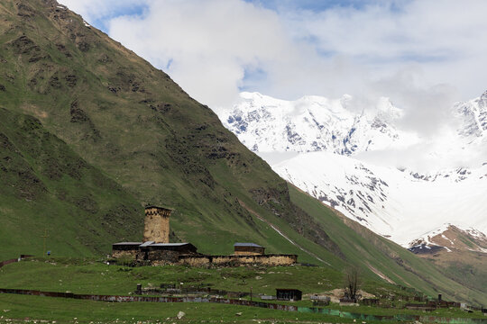 Lamaria Church and Svan tower beneath snowy Caucasus mountains