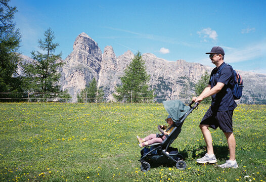 Father pushing his daughter in a stroller in the mountains