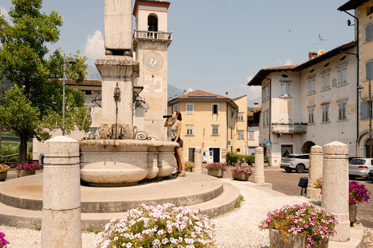 Woman cyclist drinking water in italian village square