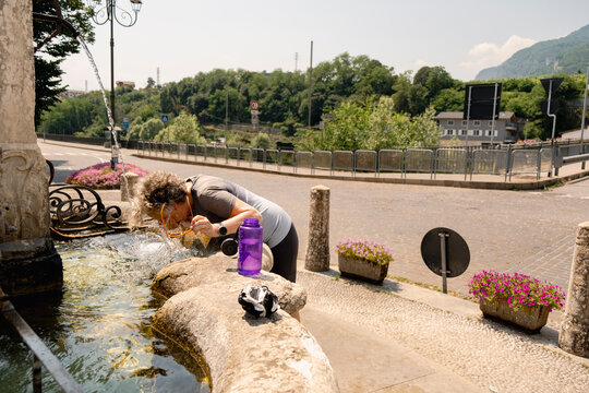 Senior cyclist cooling off at fountain during Italy bike trip