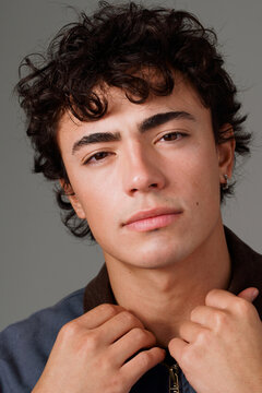 Young Man Posing With Casual Expression and Hands Near Collar