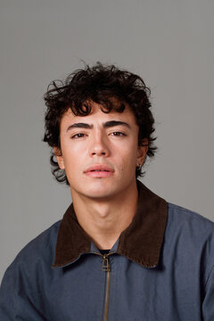 Young Man Poses Against a Plain Background With a Neutral Expression