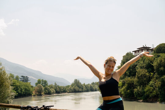 Woman cyclist celebrating by river during bikepacking trip