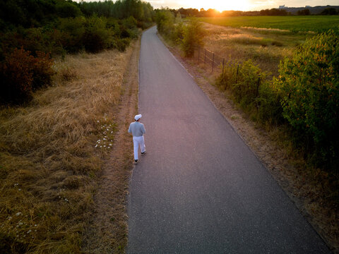 Person Walking on a Road During Sunset in a Rural Area