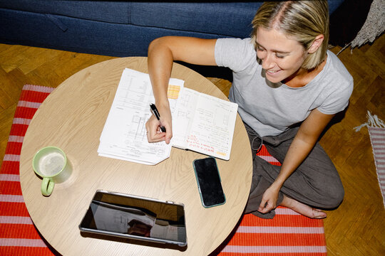 Woman architect taking notes on floor plans at night
