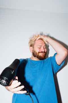 Young Man Blow Drying Hair with Wind Effect