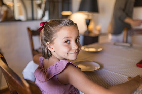 Portrait of smiling little girl sitting at dining table at home