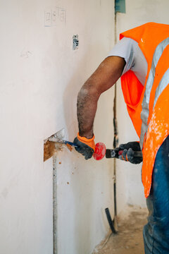 Construction worker chiseling wall channel