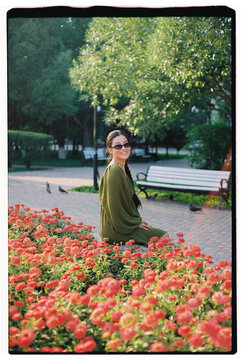 Woman Sitting by Colorful Flowers in a Park