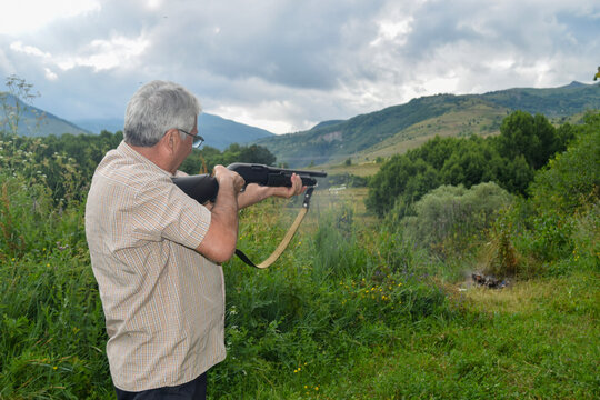 Senior Man Aiming Shotgun in Mountainous Nature Landscape