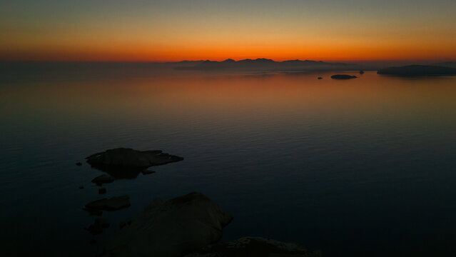 Quiet early pre dawn sunrise with colorful sky over Aegean Sea at Mandrakia village on Greek island Milos in Greece.