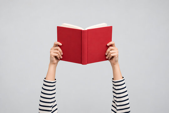 Hands holding an open red book against a light gray backdrop