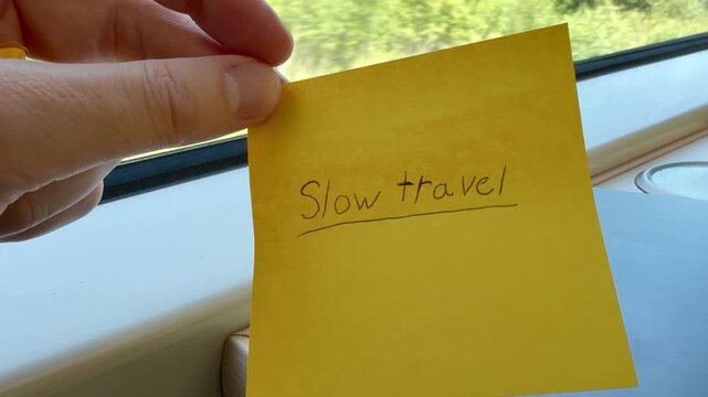 Hand Holding a Slow Travel Note at a Train Window in Finland