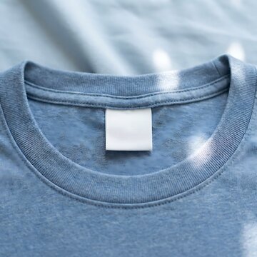Close up of a blue tshirt with a blank white inner neck clothing label for branding